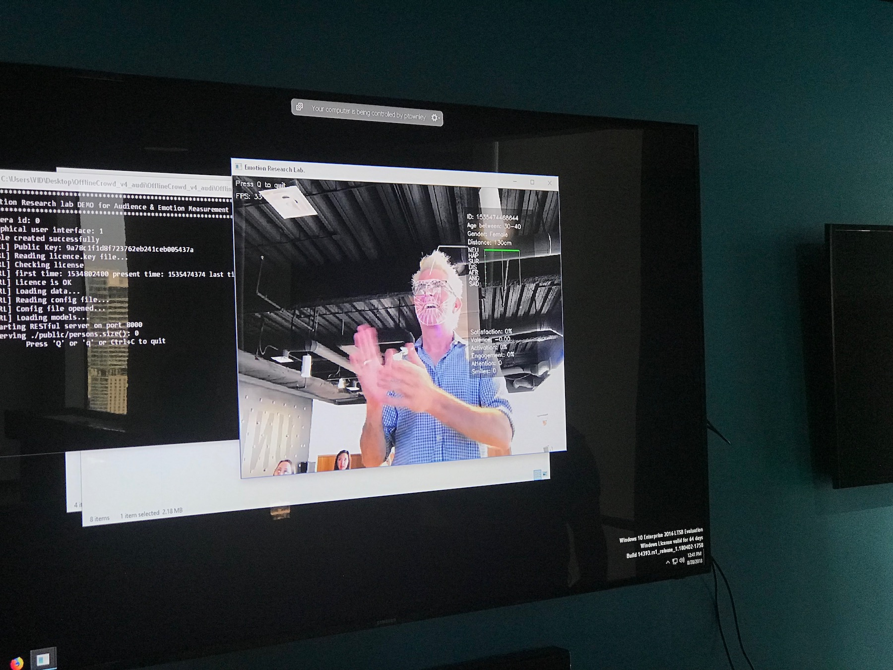 Photograph of an Emotion Research Lab demo displayed on a monitor, with a face-analysis overlay and emotion estimates.